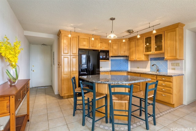 kitchen featuring backsplash, dark stone counters, a textured ceiling, sink, and a center island