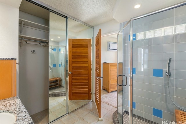 bathroom featuring tile patterned floors, vanity, an enclosed shower, and a textured ceiling