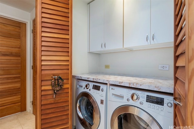 laundry room featuring washing machine and clothes dryer, light tile patterned flooring, and cabinets