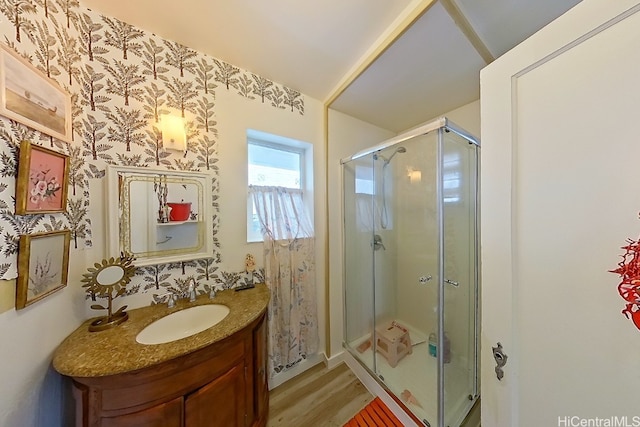 bathroom with hardwood / wood-style floors, vanity, and a shower with shower door