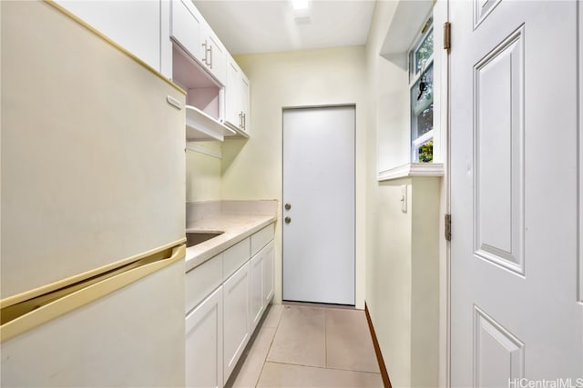 interior space featuring light tile patterned floors, white refrigerator, and white cabinetry