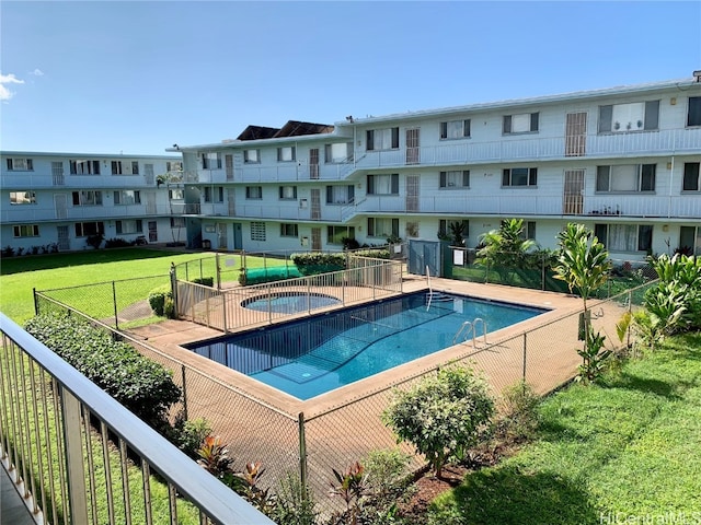 view of pool featuring a community hot tub and a lawn