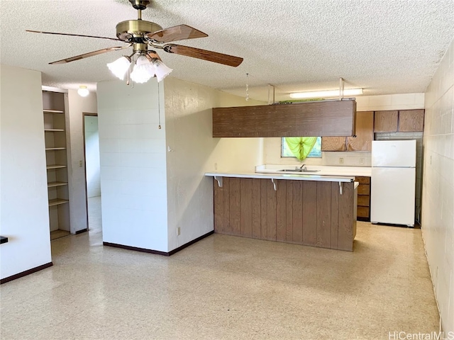 kitchen featuring white refrigerator, kitchen peninsula, and a textured ceiling