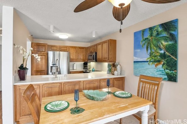 kitchen with appliances with stainless steel finishes, light countertops, a peninsula, and a textured ceiling