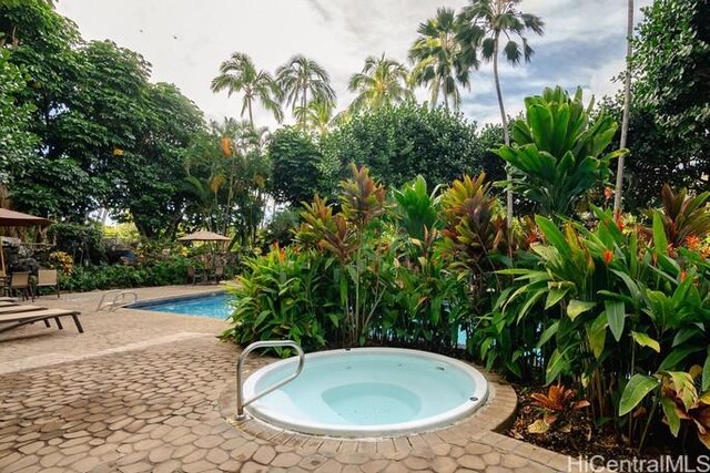 pool with a patio area and an in ground hot tub