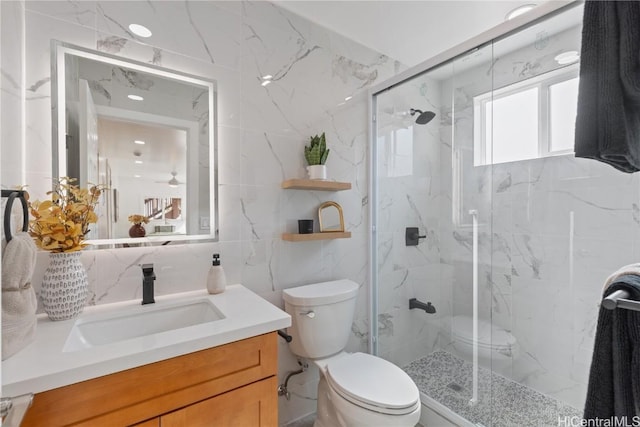 bathroom with vanity, a shower with door, toilet, and tile walls