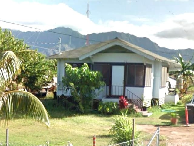 rear view of house with a mountain view and a lawn