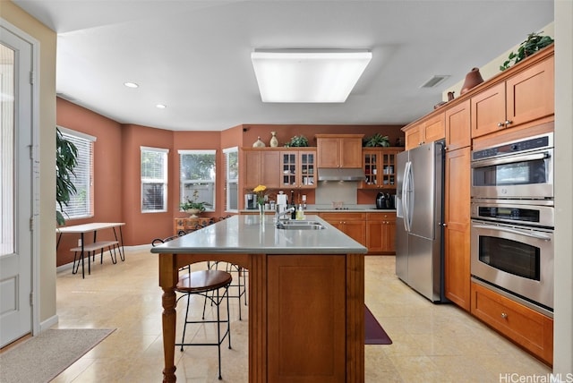 kitchen featuring a kitchen bar, appliances with stainless steel finishes, sink, an island with sink, and light tile patterned flooring