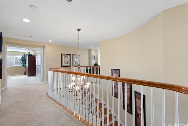 hall with a notable chandelier and light carpet