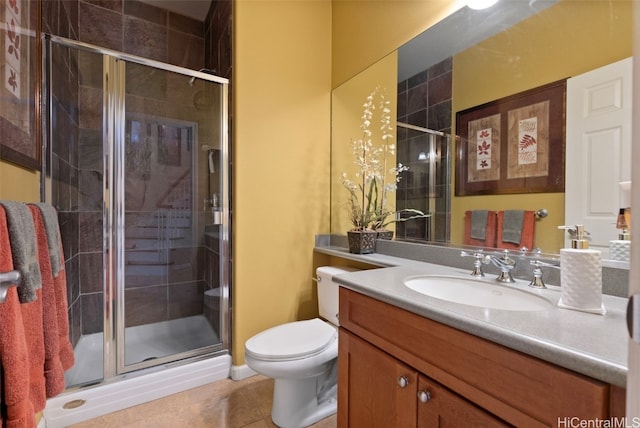 bathroom featuring tile patterned flooring, vanity, toilet, and a shower with shower door