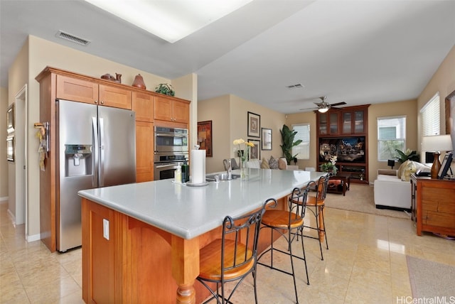 kitchen with a kitchen bar, appliances with stainless steel finishes, ceiling fan, a spacious island, and sink