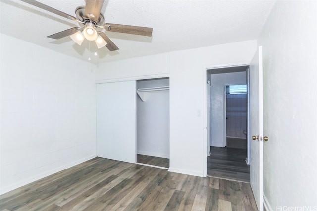 unfurnished bedroom featuring ceiling fan, a closet, dark wood-type flooring, and a textured ceiling