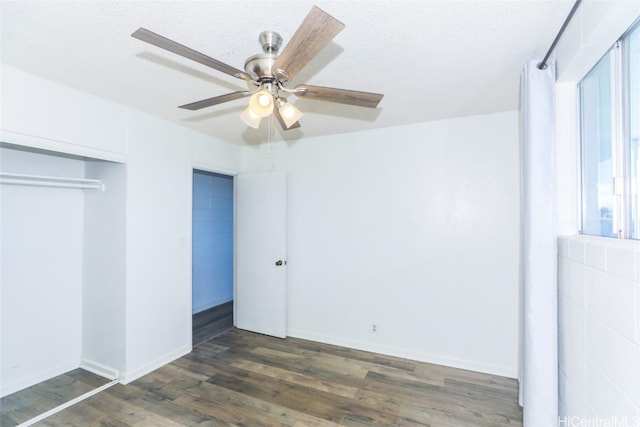 unfurnished bedroom with a closet, dark hardwood / wood-style flooring, ceiling fan, and a textured ceiling