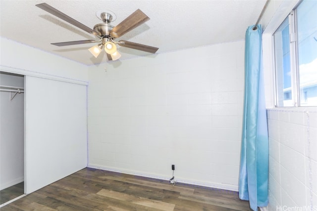 unfurnished bedroom featuring a textured ceiling, dark hardwood / wood-style flooring, a closet, and ceiling fan