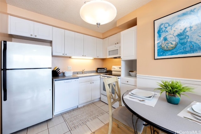 kitchen with white cabinetry, white appliances, and a textured ceiling