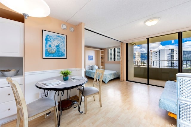 bedroom with light hardwood / wood-style floors, a wall of windows, and a textured ceiling