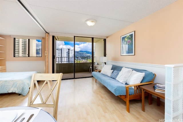 bedroom featuring access to exterior, a wall of windows, light hardwood / wood-style flooring, and multiple windows