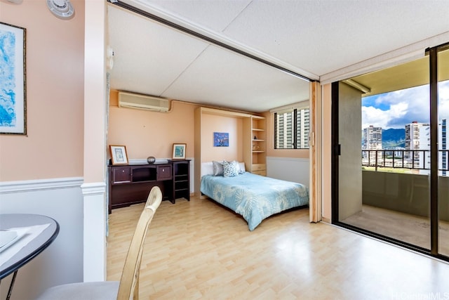 bedroom with a wall mounted AC and hardwood / wood-style flooring