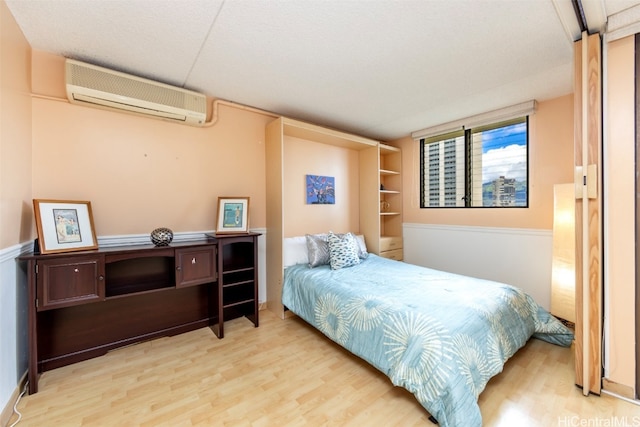 bedroom featuring wood-type flooring and a wall mounted AC