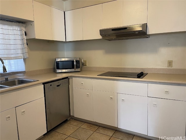 kitchen with appliances with stainless steel finishes, extractor fan, sink, light tile patterned floors, and white cabinets