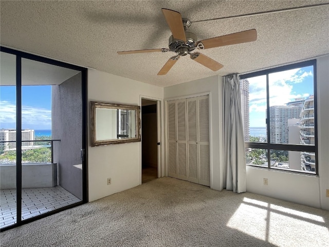 unfurnished bedroom with carpet, a textured ceiling, a closet, and multiple windows