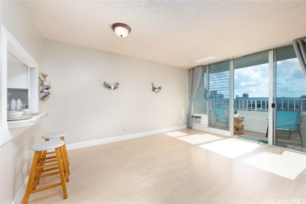 spare room with floor to ceiling windows, a wall mounted air conditioner, a textured ceiling, and wood-type flooring