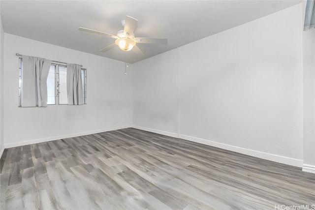 spare room featuring wood finished floors, a ceiling fan, and baseboards