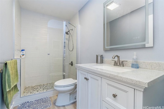 bathroom with wood finished floors, a shower stall, toilet, and vanity