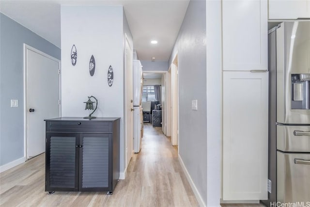 hallway featuring light wood-type flooring and baseboards