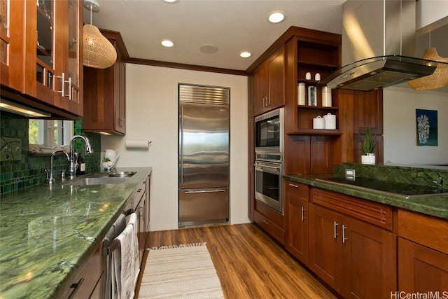 kitchen with sink, island range hood, black appliances, light wood-type flooring, and backsplash