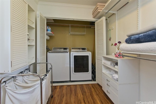 clothes washing area with ornamental molding, dark hardwood / wood-style flooring, and washing machine and dryer