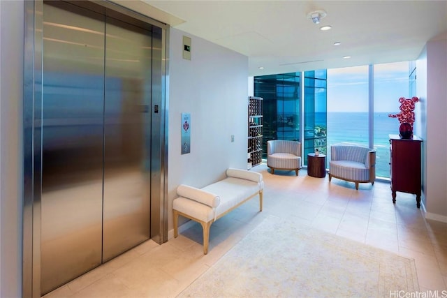 living area with expansive windows, a water view, light tile patterned flooring, and elevator