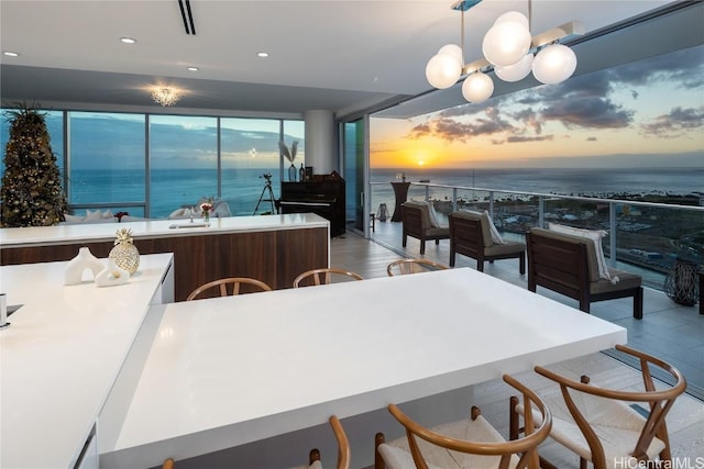 kitchen featuring floor to ceiling windows, a water view, decorative light fixtures, and an inviting chandelier