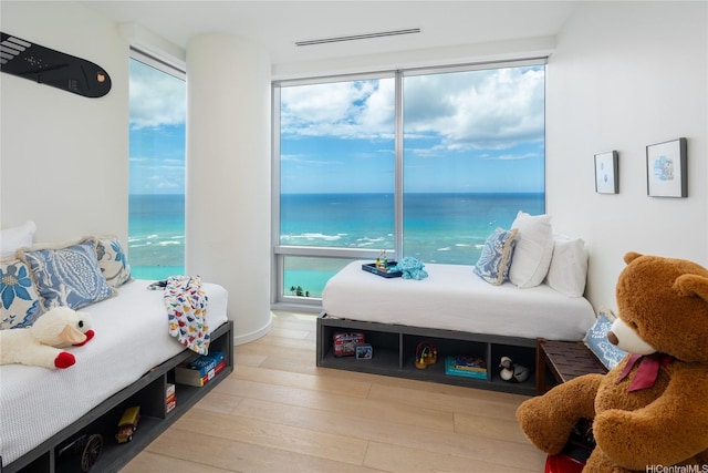 bedroom featuring wood finished floors, visible vents, and a water view