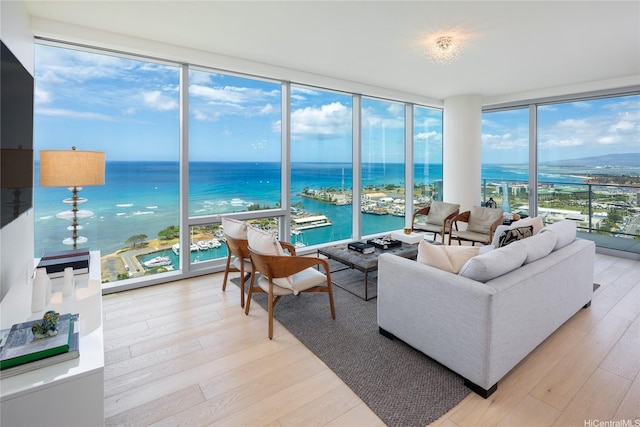 living room with floor to ceiling windows, light wood-type flooring, and a water view