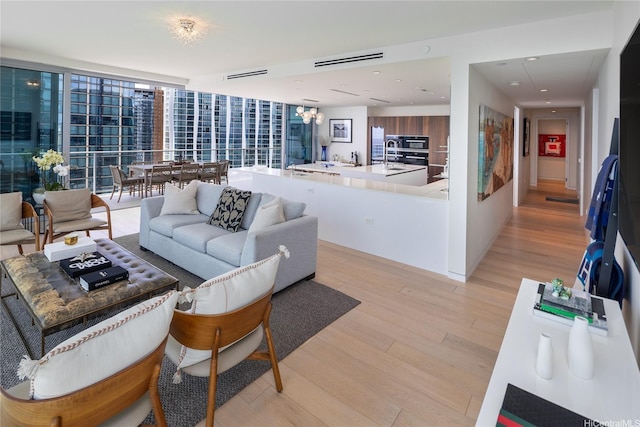 living room with visible vents, recessed lighting, light wood-style flooring, and a notable chandelier
