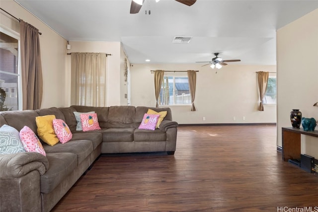 living room with a wealth of natural light, dark wood-type flooring, and ceiling fan