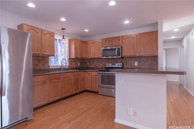 kitchen featuring sink, hanging light fixtures, decorative backsplash, light hardwood / wood-style floors, and stainless steel appliances