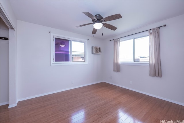 unfurnished room with an AC wall unit, ceiling fan, and light hardwood / wood-style flooring