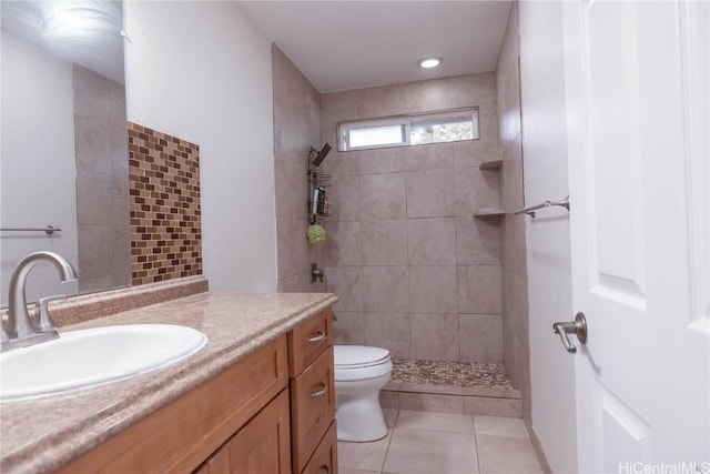 bathroom with tile patterned floors, vanity, toilet, and a tile shower