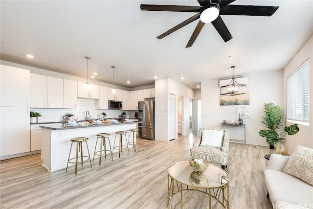 living room with ceiling fan with notable chandelier and light wood-type flooring