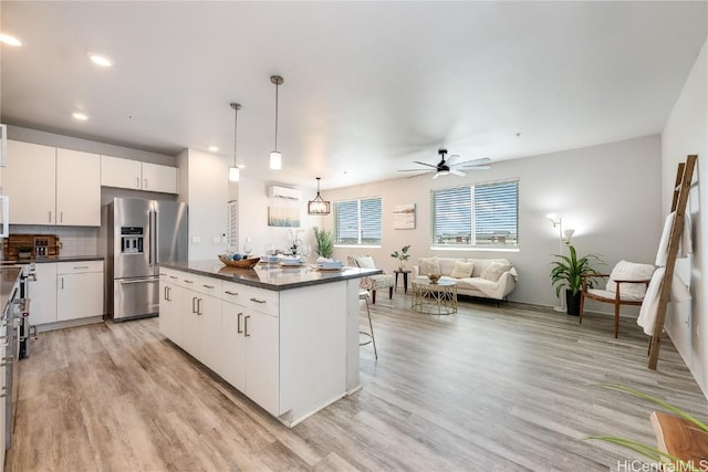 kitchen with stainless steel fridge, a kitchen island, ceiling fan, decorative light fixtures, and white cabinetry