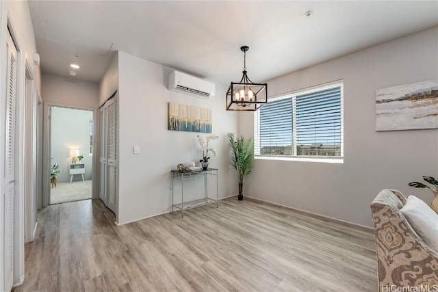 unfurnished dining area with an AC wall unit, an inviting chandelier, and light wood-type flooring