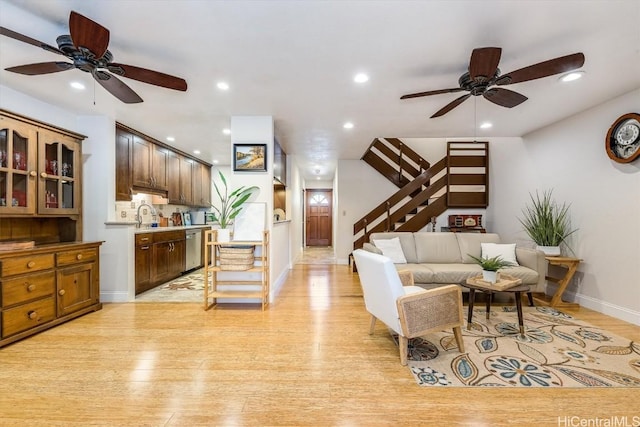 living room with light hardwood / wood-style flooring, ceiling fan, and sink