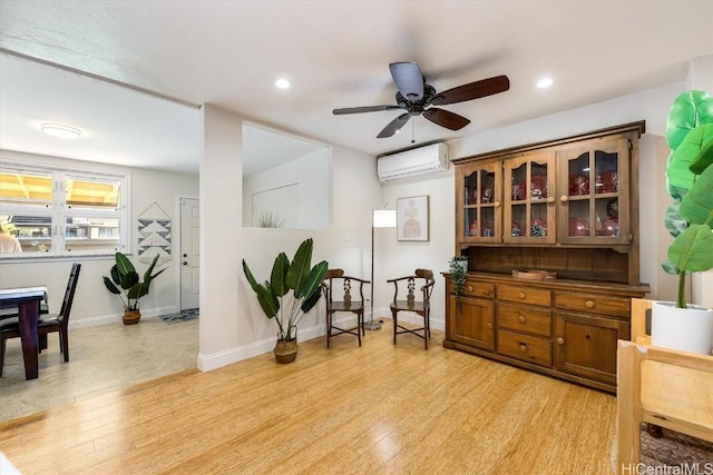 sitting room featuring ceiling fan, light hardwood / wood-style floors, and an AC wall unit