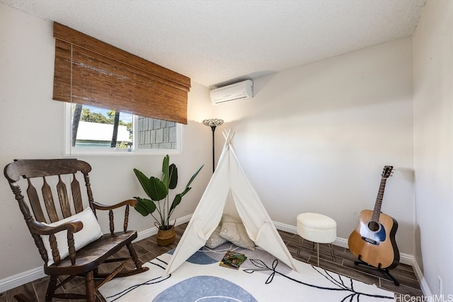 recreation room featuring hardwood / wood-style flooring, a textured ceiling, and a wall mounted AC