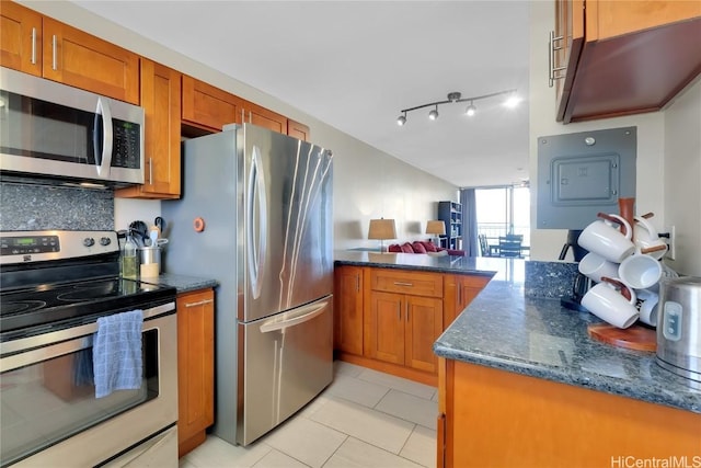 kitchen with dark stone countertops, electric panel, decorative backsplash, light tile patterned floors, and appliances with stainless steel finishes