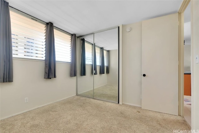 unfurnished bedroom with multiple windows, a closet, and light colored carpet