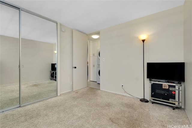 unfurnished living room featuring carpet and stacked washer and dryer