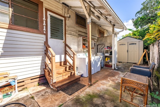 view of patio / terrace with washer and clothes dryer and a storage shed